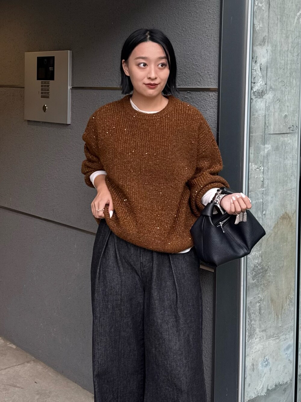 ブラウン系のニット/セーター、ブラック系のデニムパンツ、ブラック系のトートバッグを着用したレディースの秋コーディネートの3枚目の写真