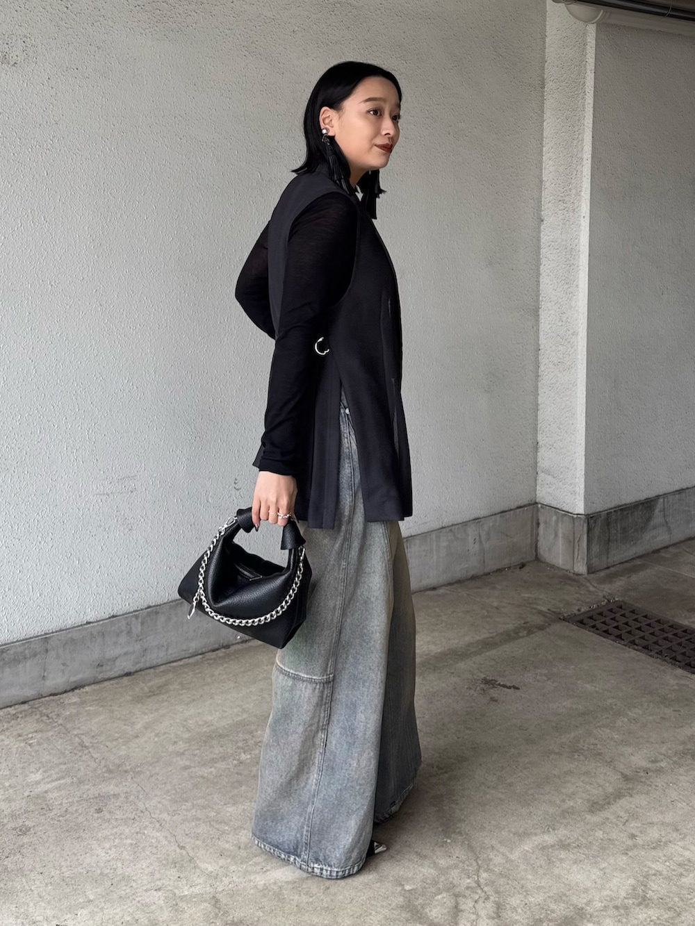 グレー系のベスト、ブラック系のTシャツ/カットソー、ブラック系のデニムパンツを着用したレディースの春コーディネートの2枚目の写真