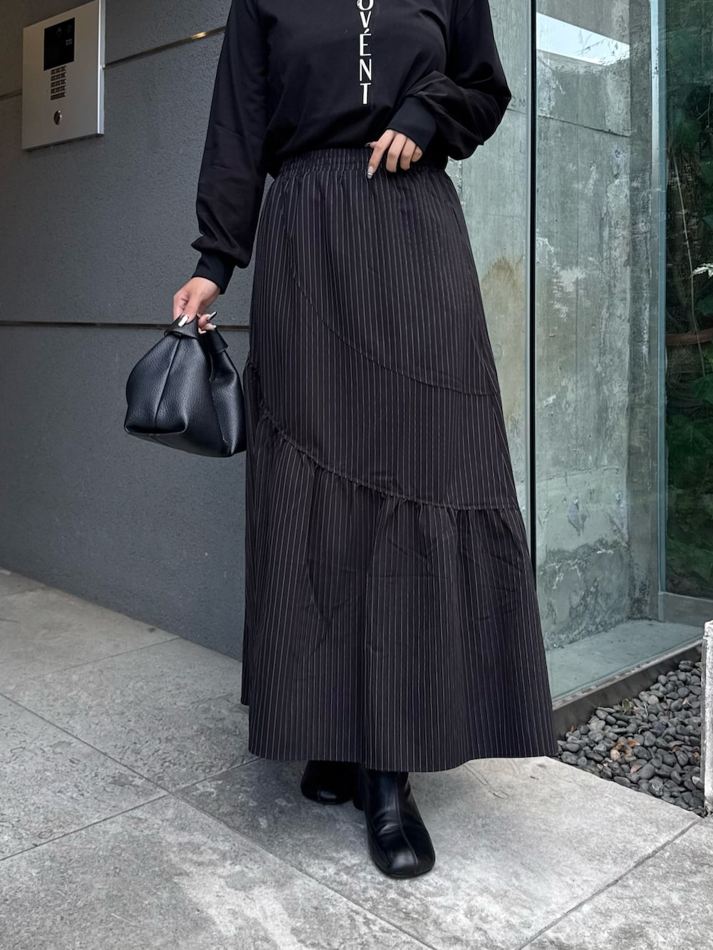 ブラック系のTシャツ/カットソー、ブラック系のスカート、ブラック系のトートバッグを着用したレディースの秋コーディネートの6枚目の写真