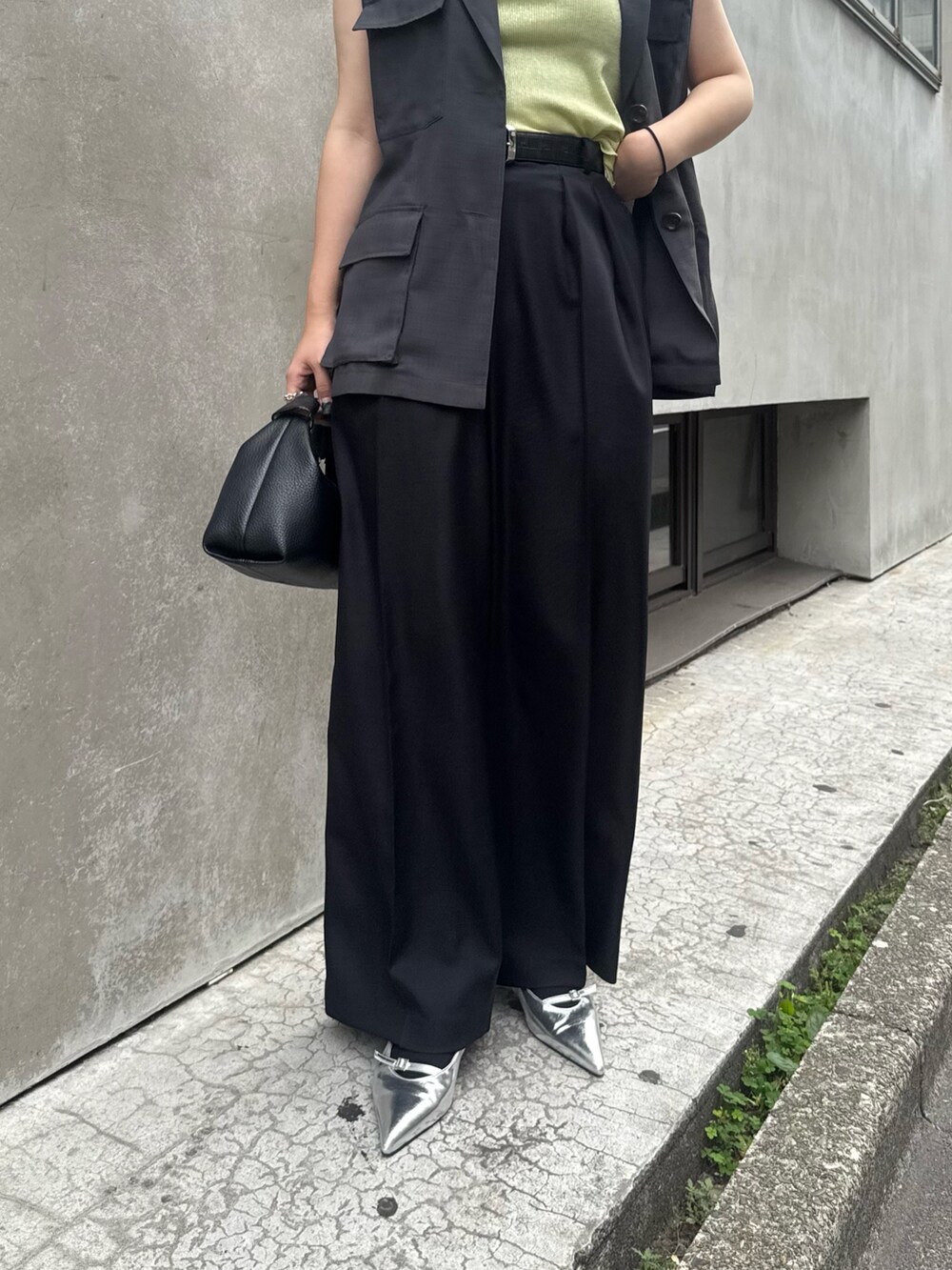 グレー系のベスト、グリーン系のタンクトップ、ブラック系のスラックスを着用したレディースの夏コーディネートの5枚目の写真