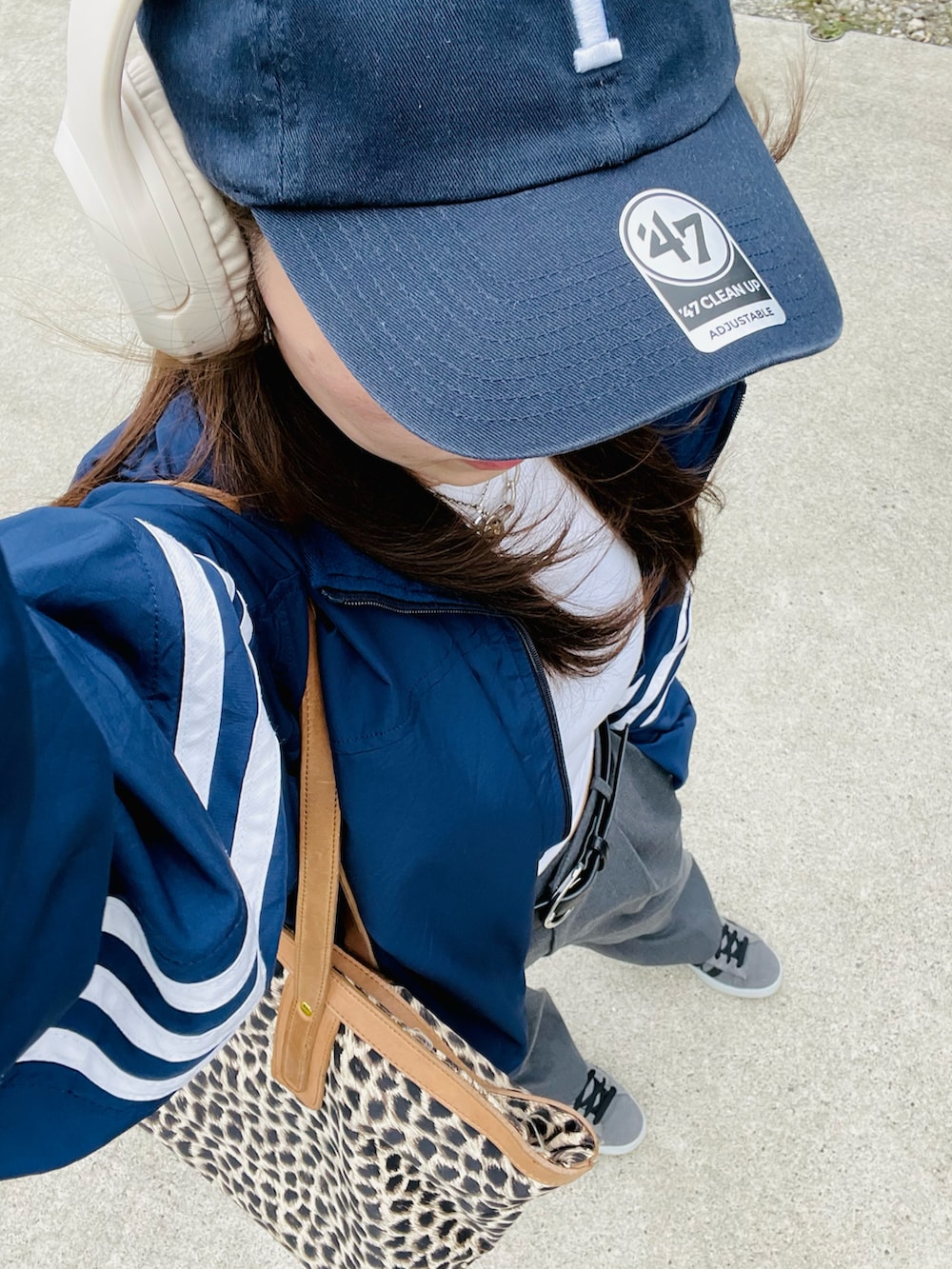 グレー系のスラックス、グレー系のスニーカー、ブルー系のナイロンジャケットを着用したレディースの秋コーディネートの3枚目の写真