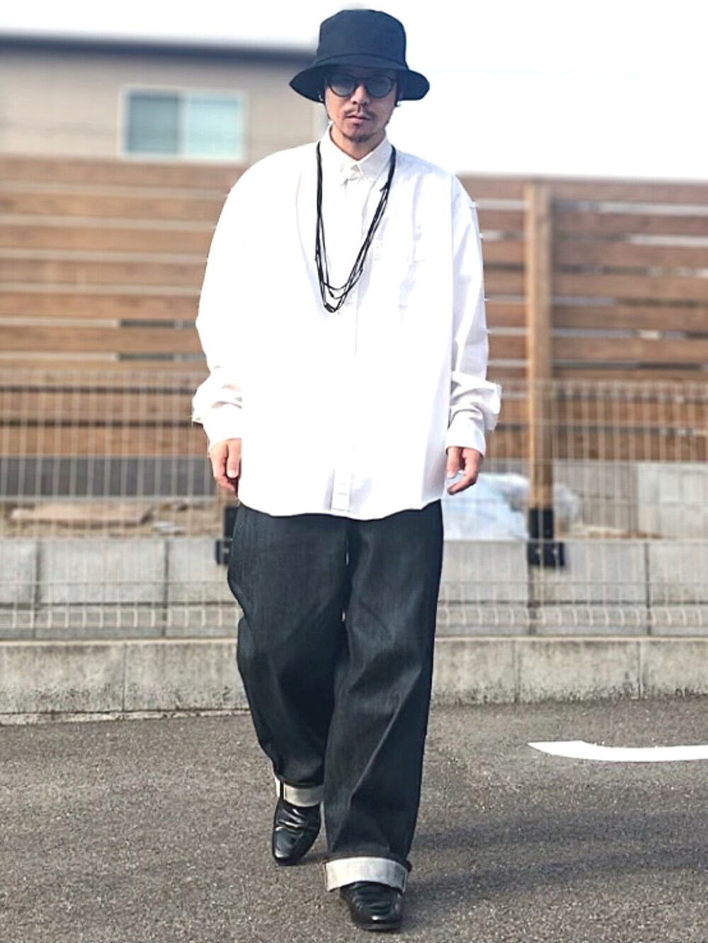 ブルー系のデニムパンツ、グリーン系のブレスレット、ブラック系のハットを着用したメンズの春コーディネートの2枚目の写真