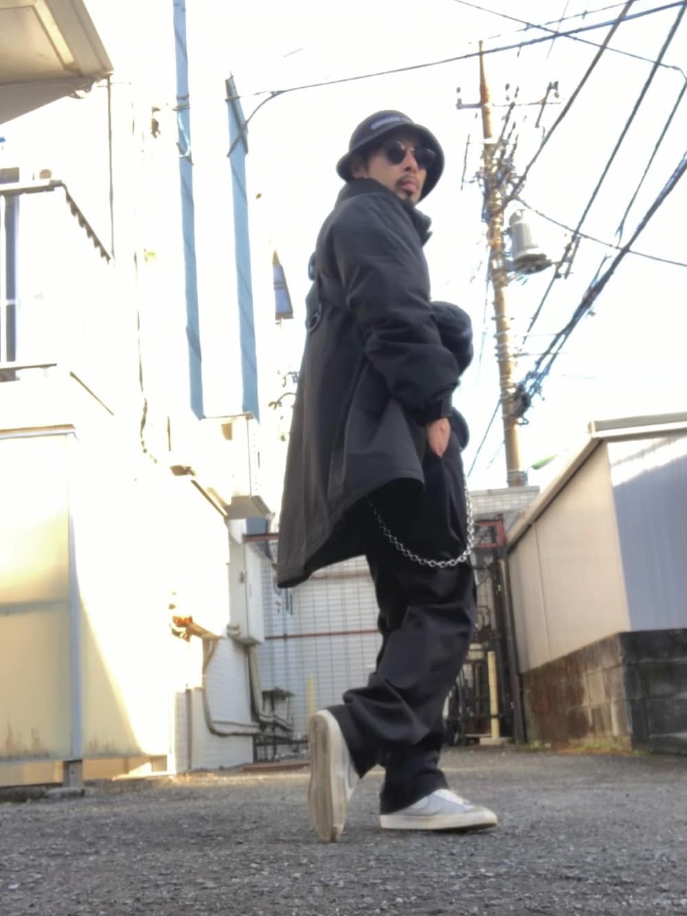 ブラック系のチノパンツ、ホワイト系のスニーカー、ブラック系のボディバッグ/ウエストポーチを着用したメンズの冬コーディネートの2枚目の写真