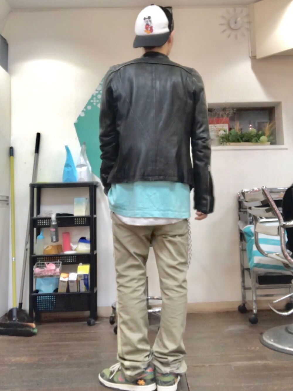 ブラック系のライダースジャケット、グリーン系のTシャツ/カットソー、ベージュ系のチノパンツを着用したメンズの秋コーディネートの2枚目の写真