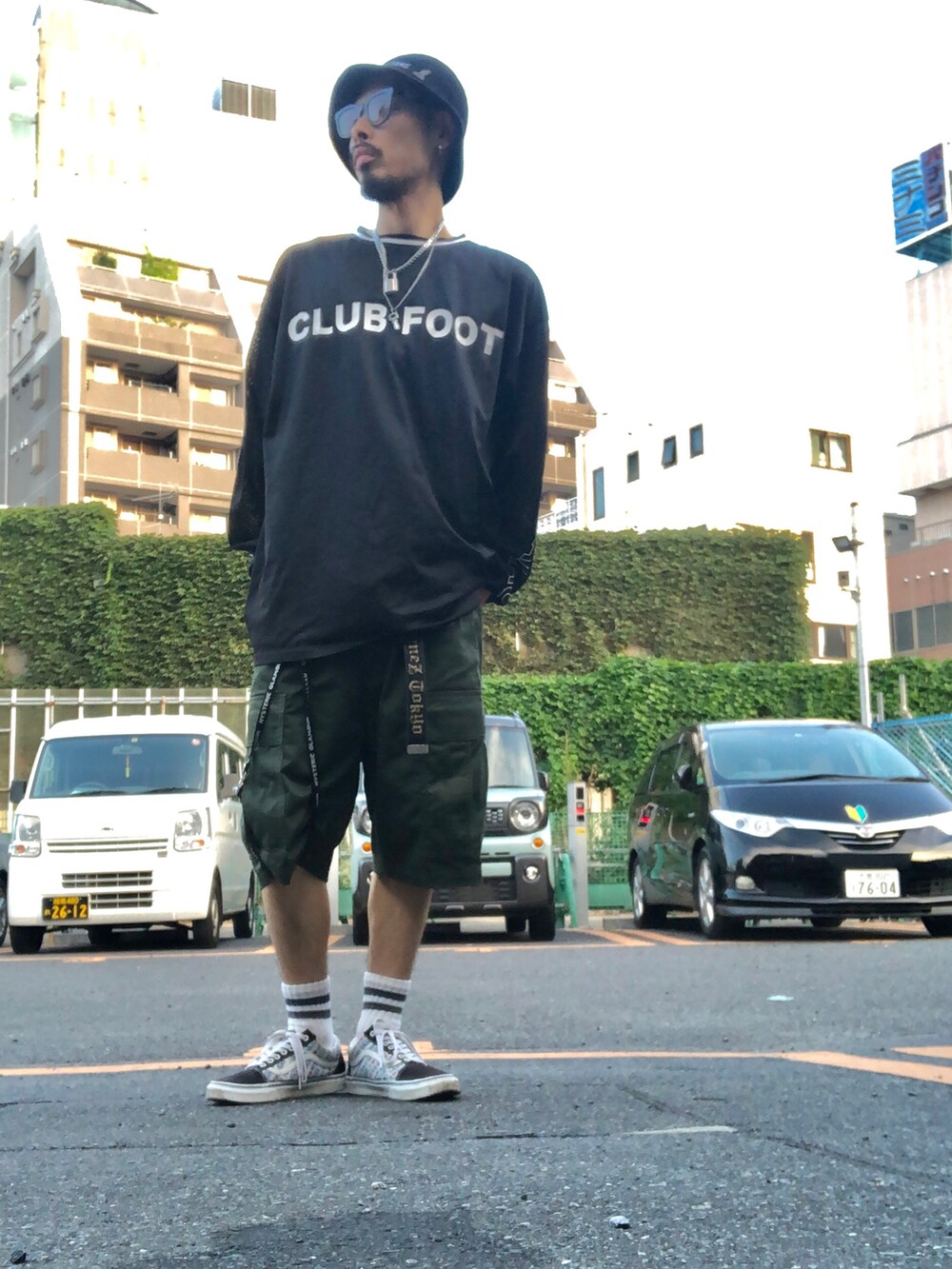 グリーン系のカーゴパンツ、ブラック系のスニーカー、ブラック系のハットを着用したメンズの夏コーディネートの2枚目の写真