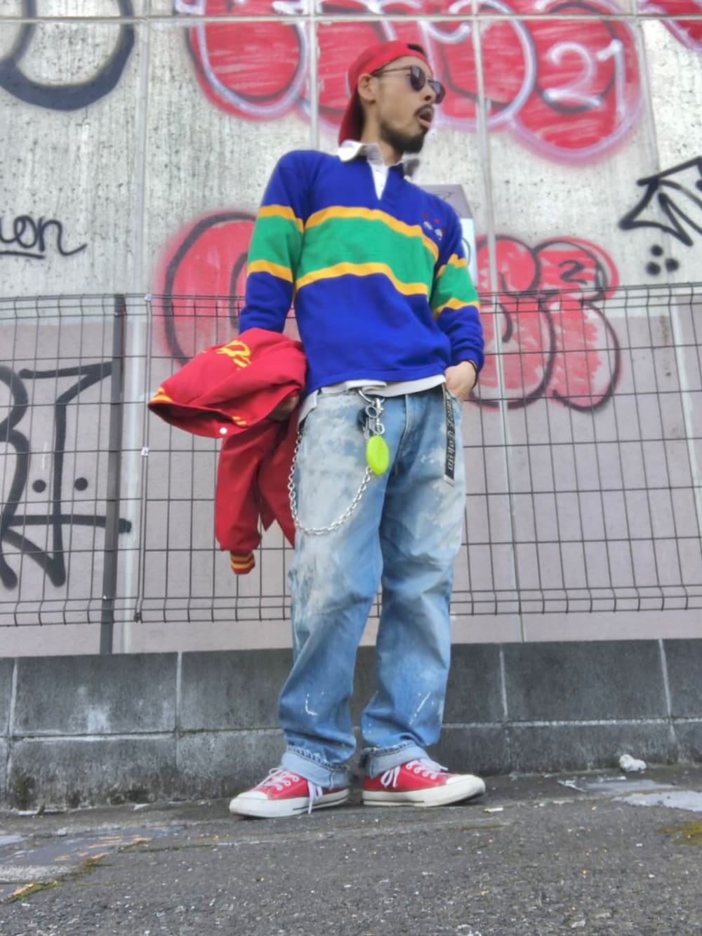 レッド系のスタジャン、ブルー系のポロシャツ、ブルー系のデニムパンツを着用したメンズの春コーディネートの2枚目の写真