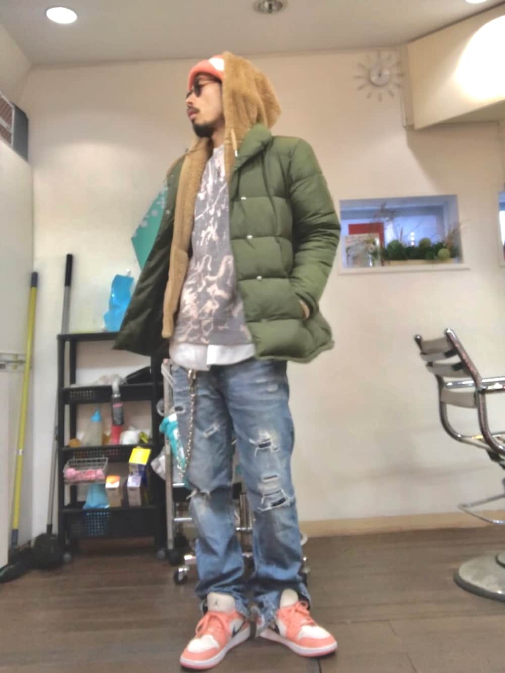 ベージュ系のパーカー、グリーン系のダウンジャケット/コート、ブルー系のデニムパンツを着用したメンズの冬コーディネートの2枚目の写真