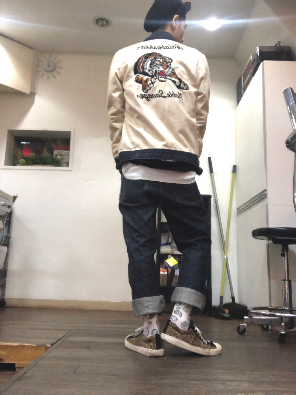 ベージュ系のブルゾン、ブラック系のカーディガン/ボレロ、ブルー系のデニムパンツを着用したメンズの秋コーディネートの2枚目の写真