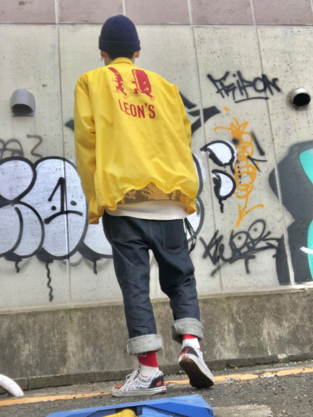 イエロー系のナイロンジャケット、グレー系のスウェット、ブルー系のデニムパンツを着用したメンズの春コーディネートの2枚目の写真