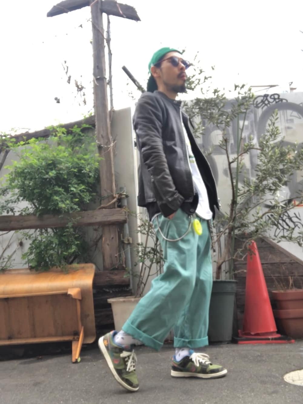 ブラック系のライダースジャケット、グリーン系のTシャツ/カットソー、グリーン系のチノパンツを着用したメンズの春コーディネートの2枚目の写真