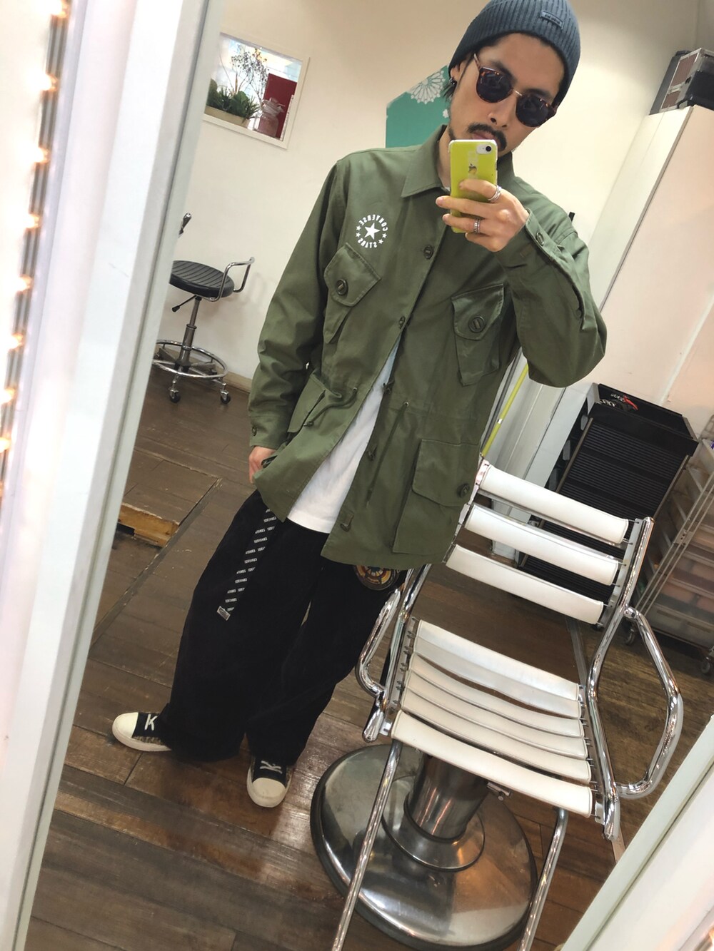 グリーン系のミリタリージャケット、ブラック系のその他パンツ、ブラック系のスニーカーを着用したメンズの春コーディネートの2枚目の写真