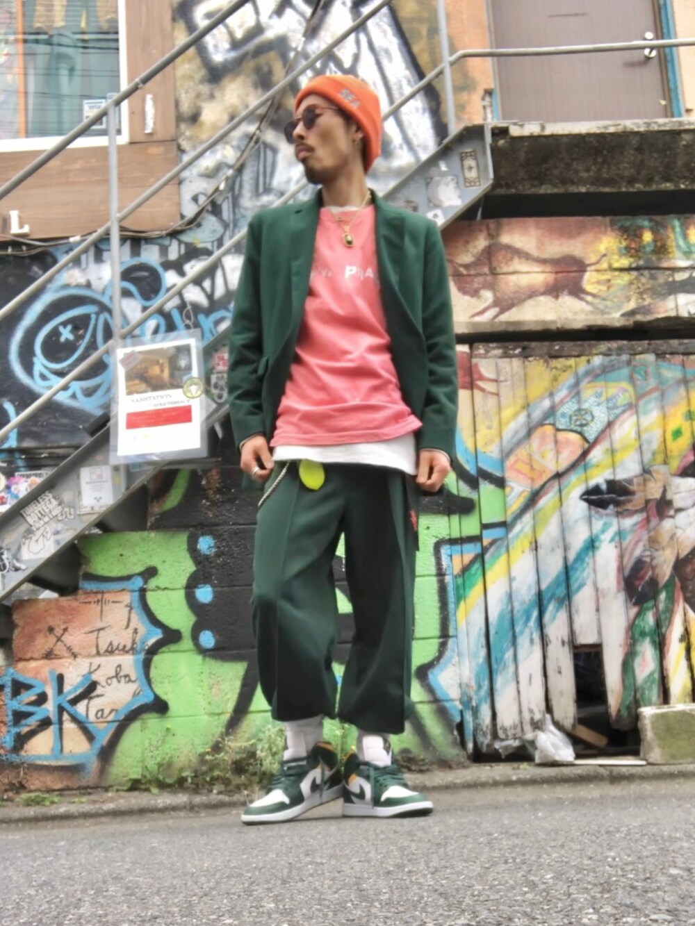 グリーン系のテーラードジャケット、オレンジ系のTシャツ/カットソー、グリーン系のスラックスを着用したメンズの春コーディネートの2枚目の写真