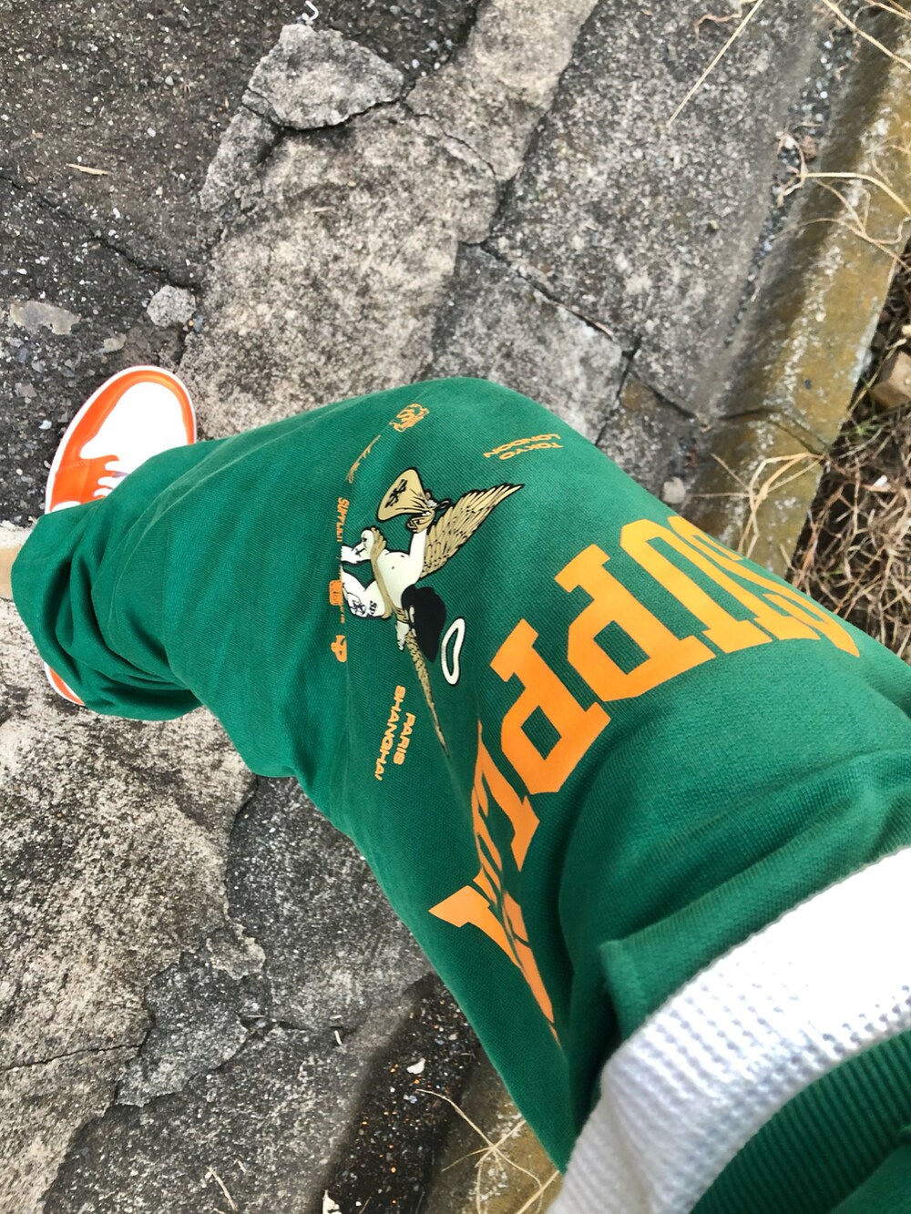 グリーン系のスウェットパンツ、ブラック系のライダースジャケット、オレンジ系のスニーカーを着用したメンズの秋コーディネートの2枚目の写真