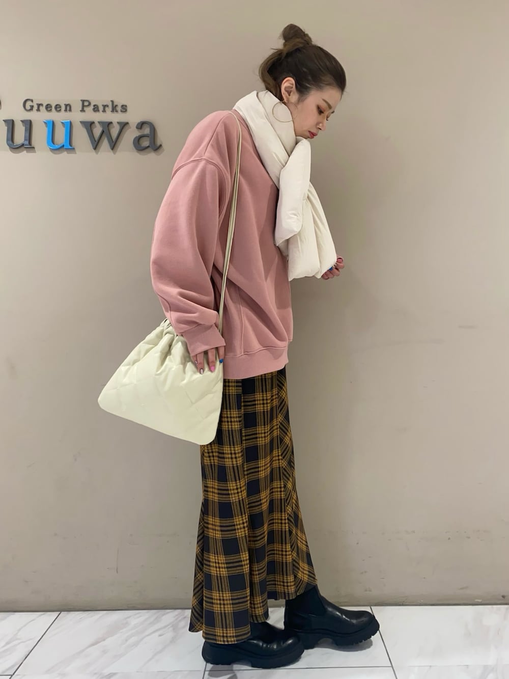 ピンク系のスウェット、イエロー系のスカート、ホワイト系のショルダーバッグを着用したレディースの冬コーディネートの3枚目の写真