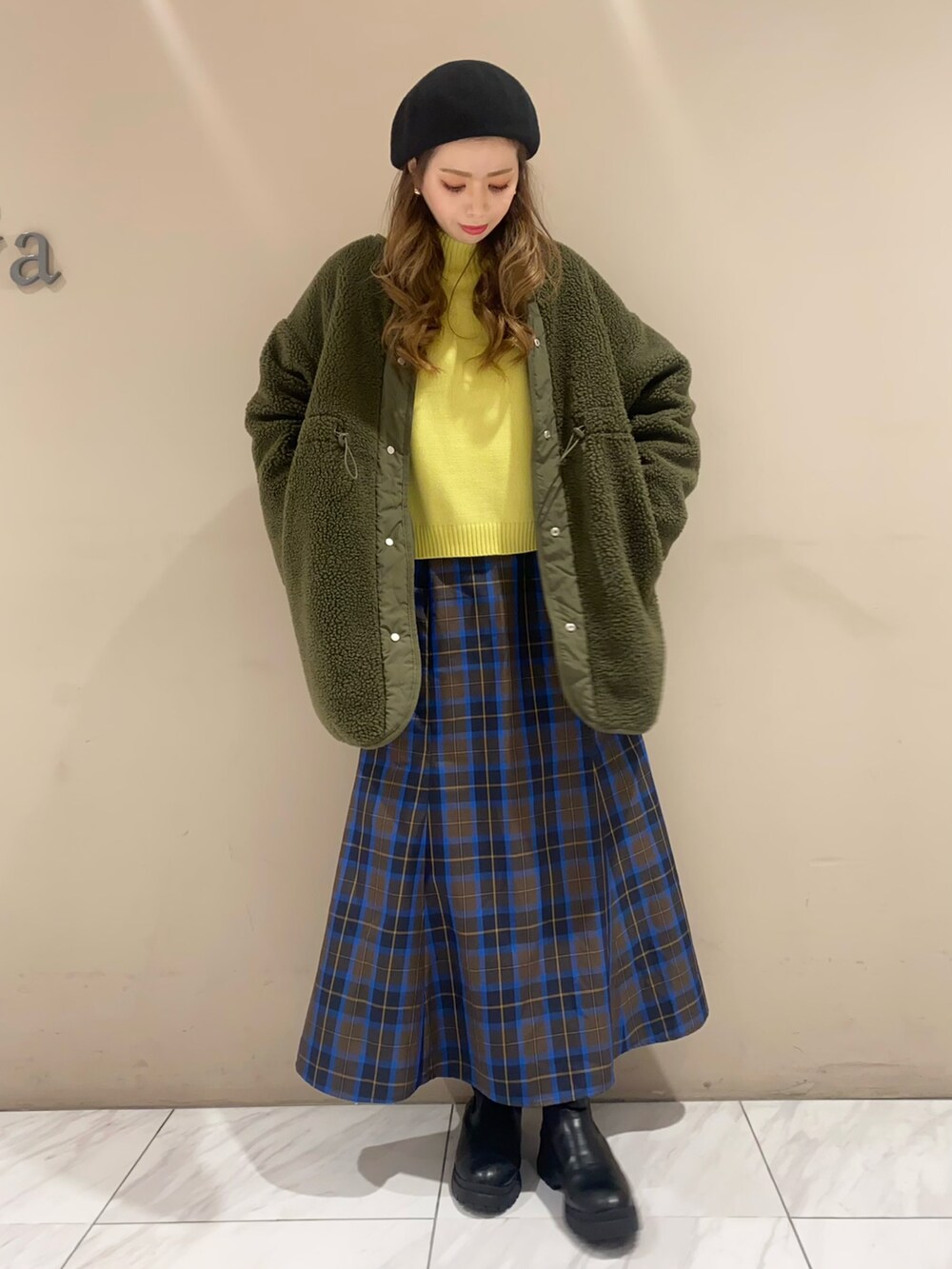 ブルー系のスカート、イエロー系のニット/セーター、グリーン系のその他アウターを着用したレディースの冬コーディネートの3枚目の写真