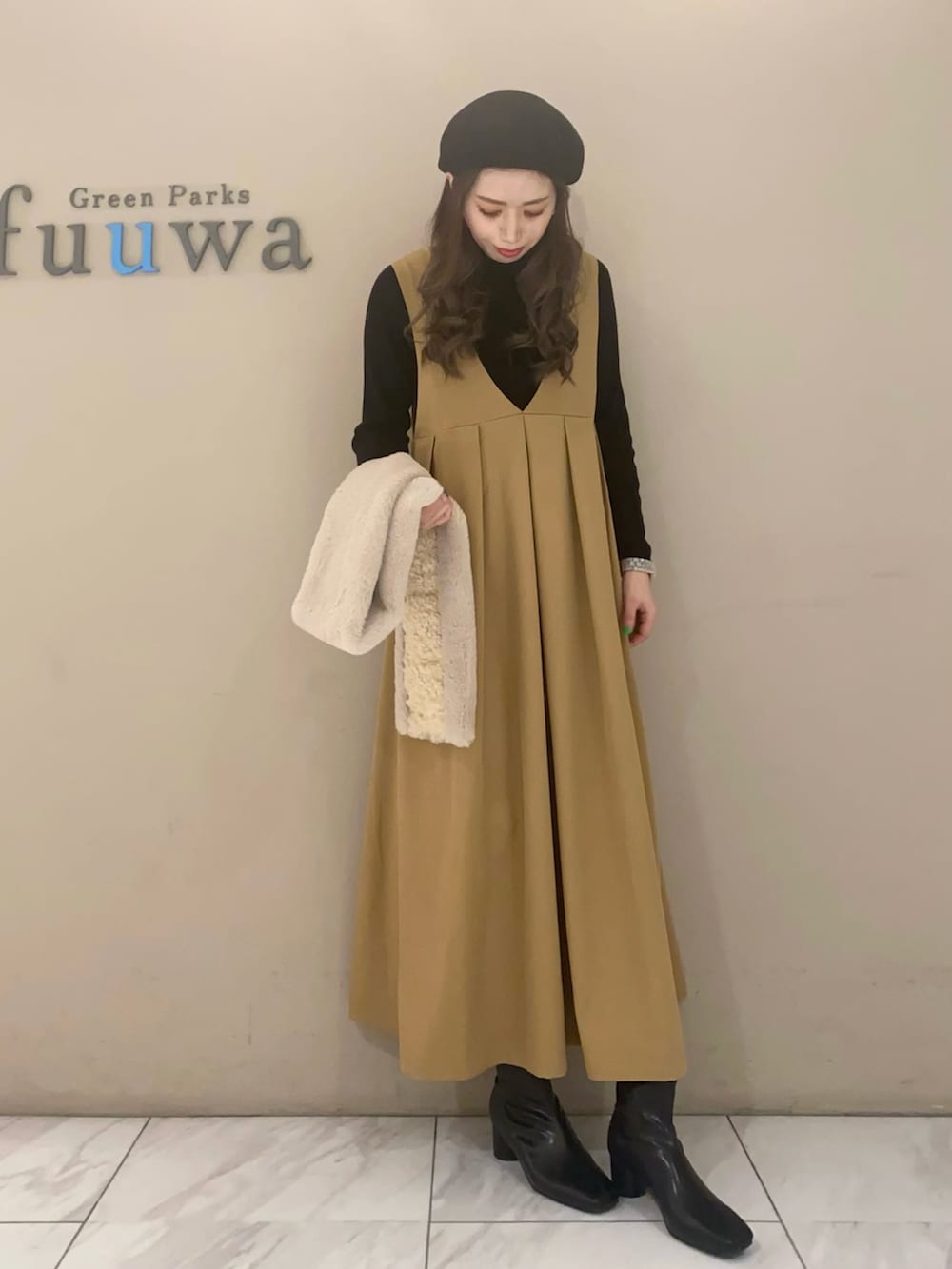 ベージュ系のジャンパースカート、ブラック系のニット/セーター、ブラック系のブーツを着用したレディースの冬コーディネートの3枚目の写真