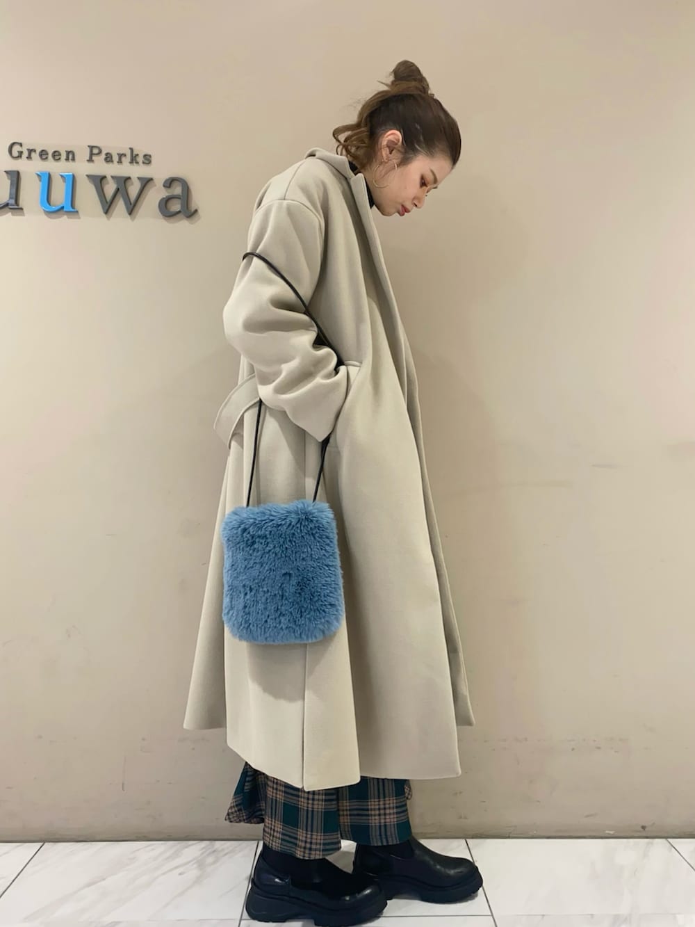 イエロー系のスカート、ブラック系のブーツ、ベージュ系のチェスターコートを着用したレディースの冬コーディネートの2枚目の写真