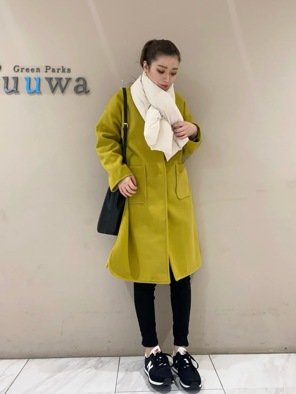 イエロー系のノーカラーコート、ブラック系のショルダーバッグ、ブラック系のパンツを着用したレディースの冬コーディネートの3枚目の写真