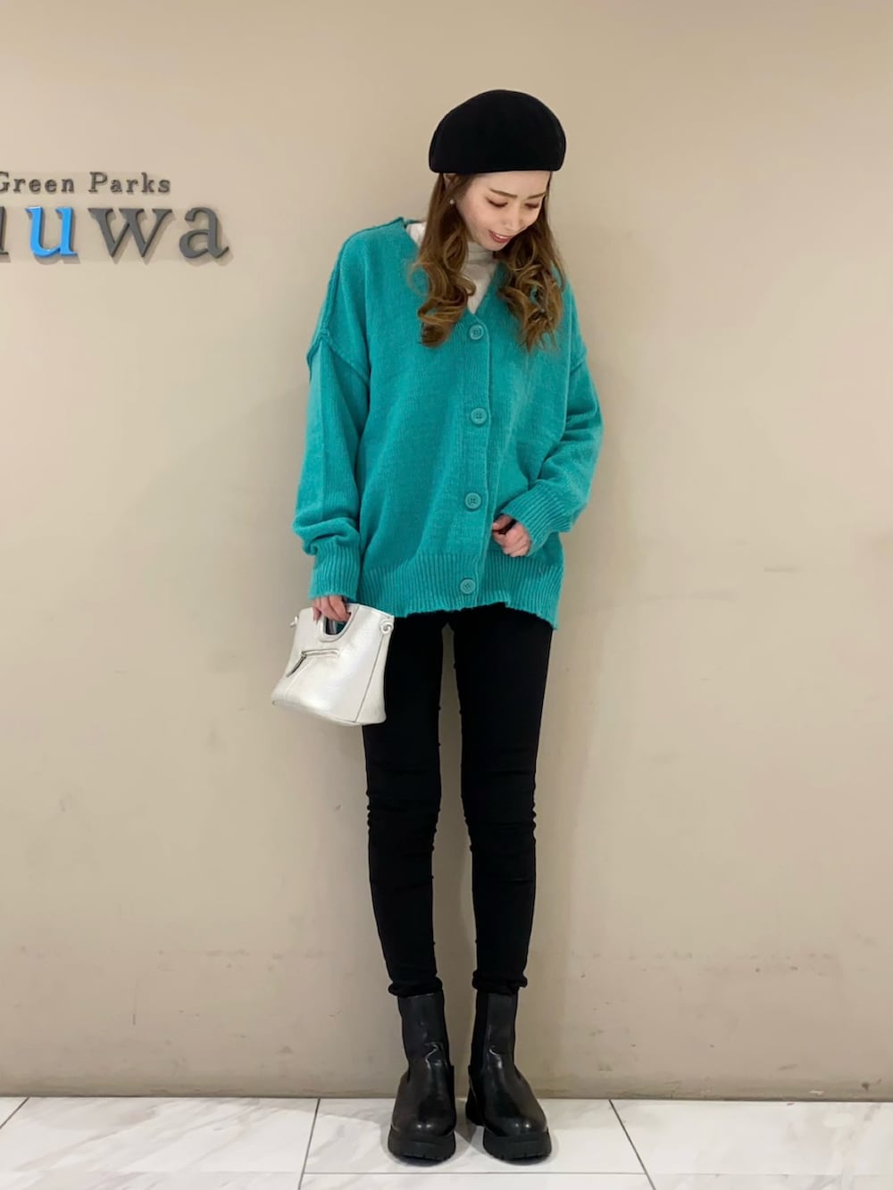 グリーン系のカーディガン/ボレロ、シルバー系のショルダーバッグ、ブラック系のパンツを着用したレディースの冬コーディネートの2枚目の写真