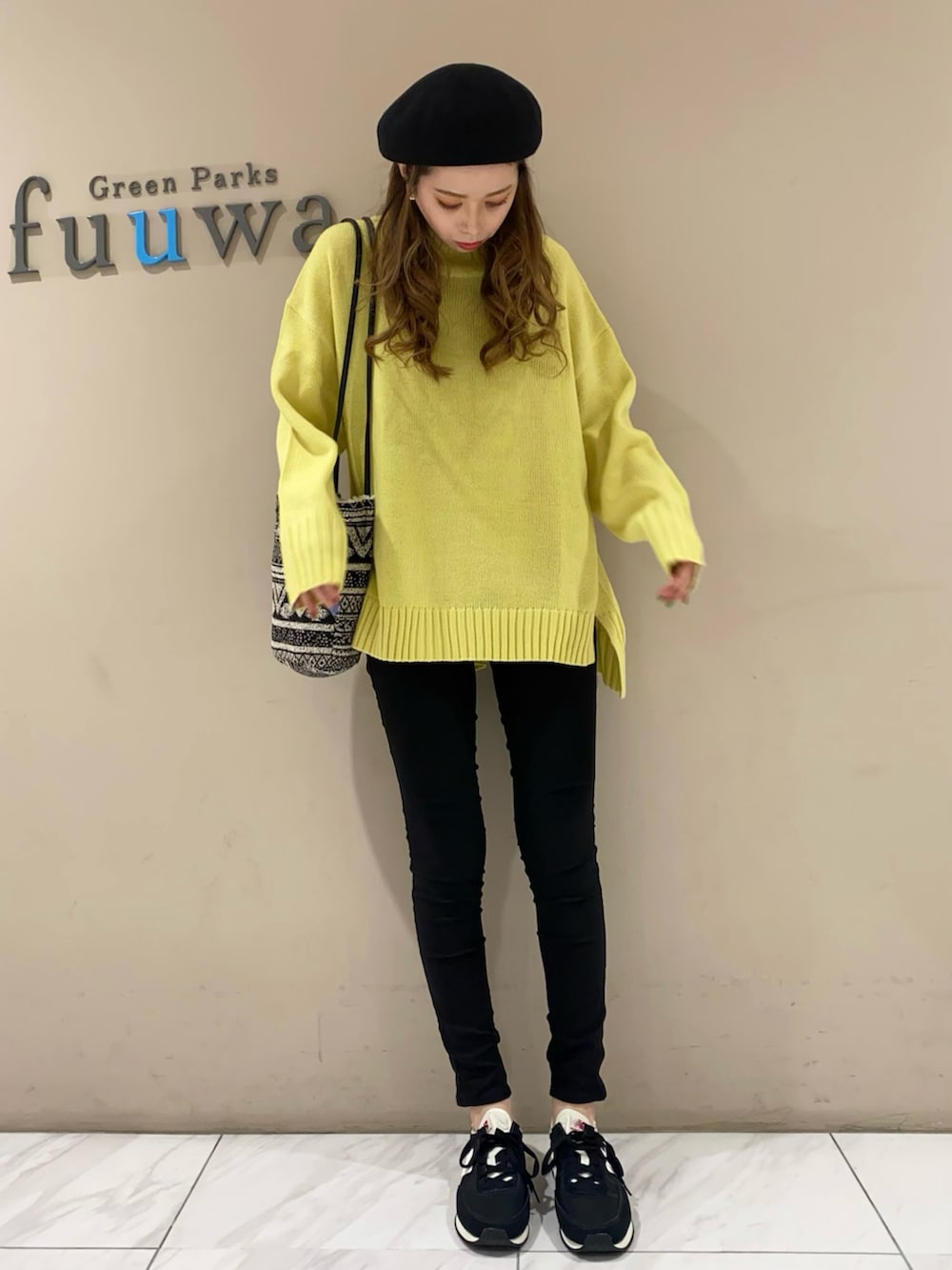 イエロー系のニット/セーター、ブラック系のトートバッグ、ブルー系のデニムパンツを着用したレディースの冬コーディネートの2枚目の写真
