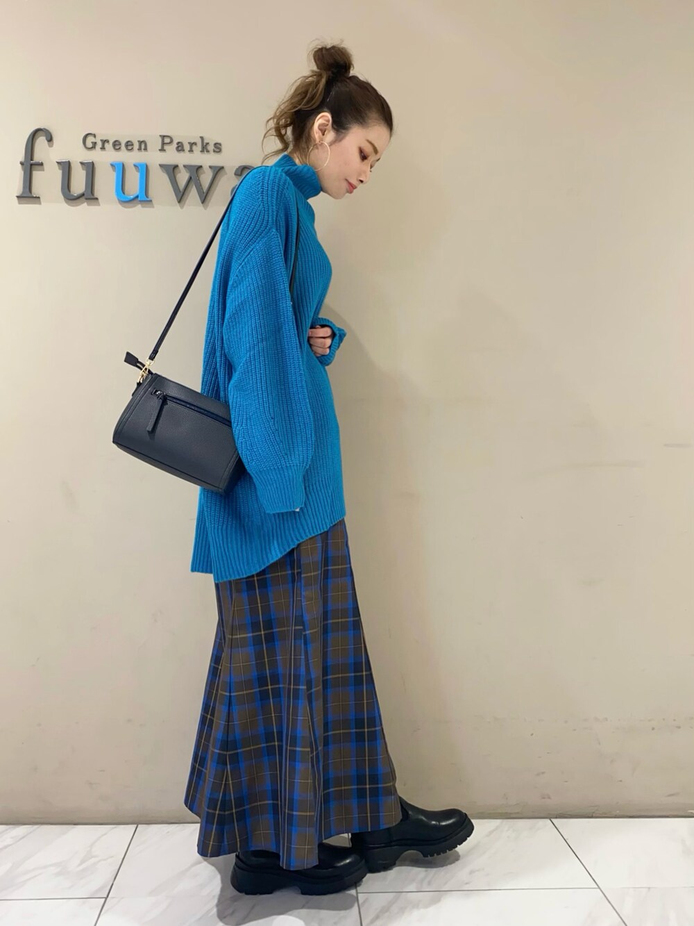 ブルー系のニット/セーター、ブルー系のスカート、ブラック系のブーツを着用したレディースの秋コーディネートの2枚目の写真
