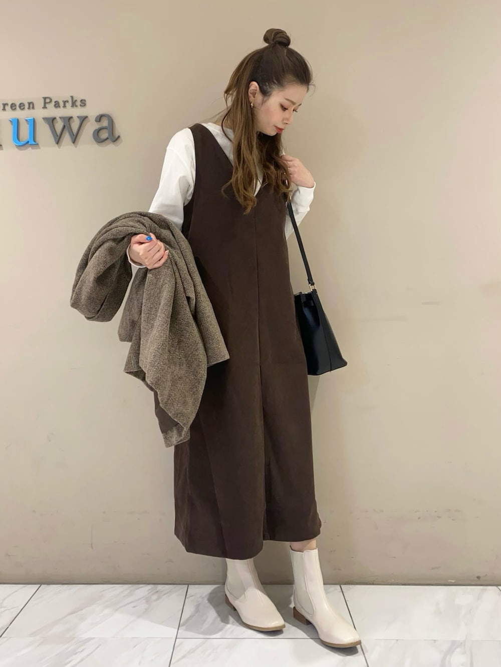 ブラウン系のジャンパースカート、ブラック系のブーツ、ブラック系のショルダーバッグを着用したレディースの冬コーディネートの3枚目の写真