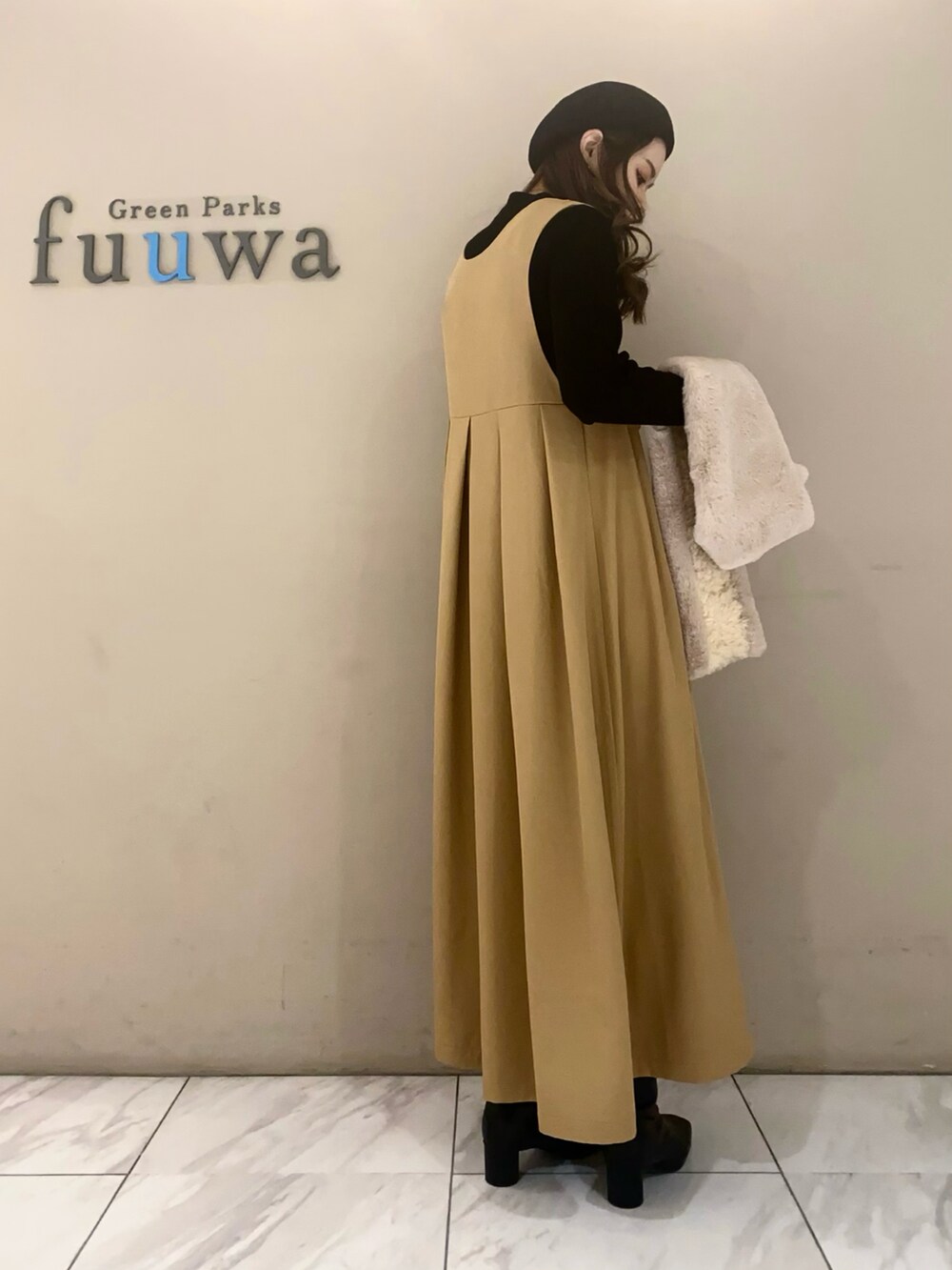 ベージュ系のジャンパースカート、ブラック系のニット/セーター、ブラック系のブーツを着用したレディースの冬コーディネートの2枚目の写真