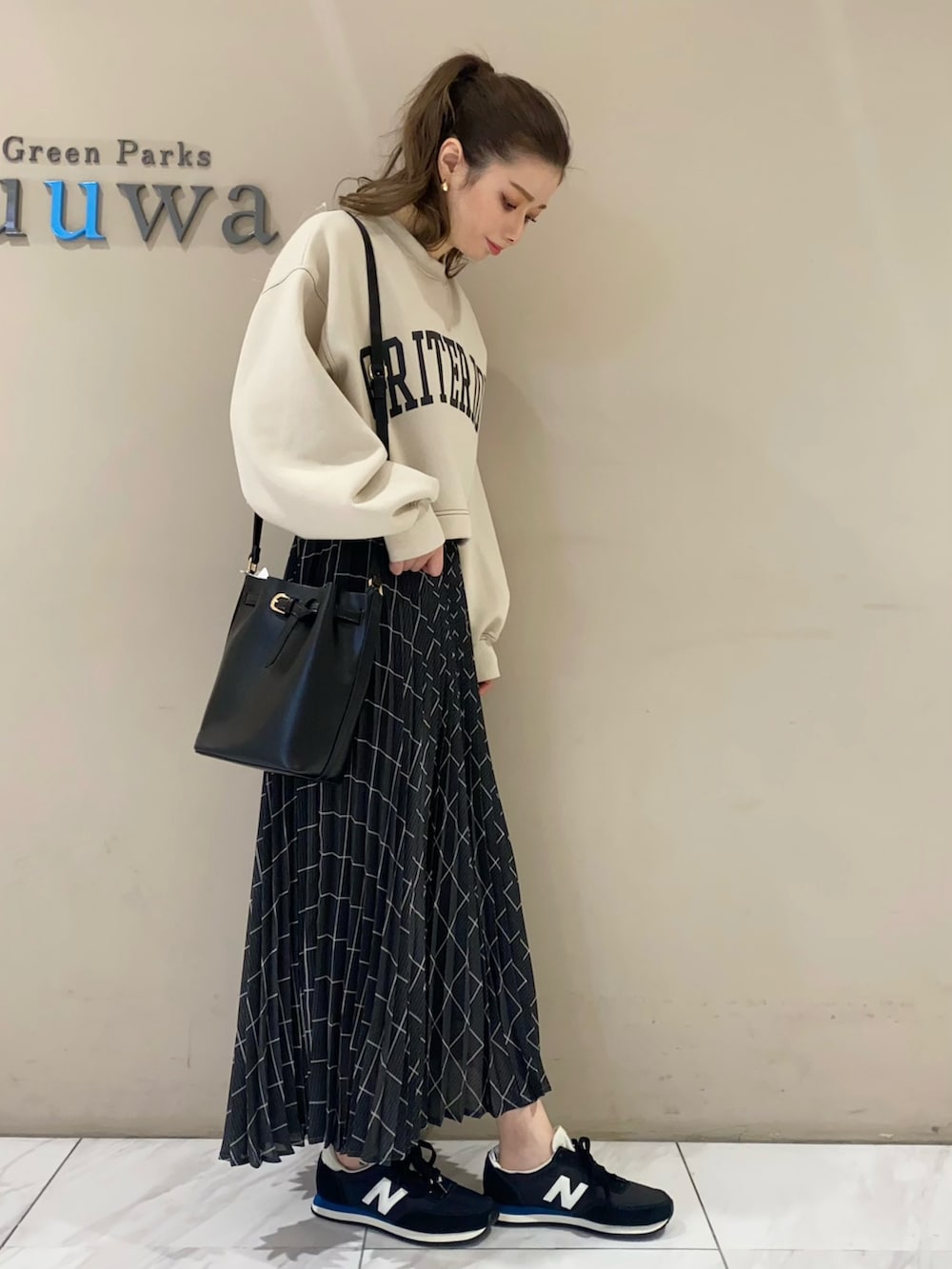 ホワイト系のスウェット、ブラック系のショルダーバッグ、グレー系のスカートを着用したレディースの冬コーディネートの2枚目の写真