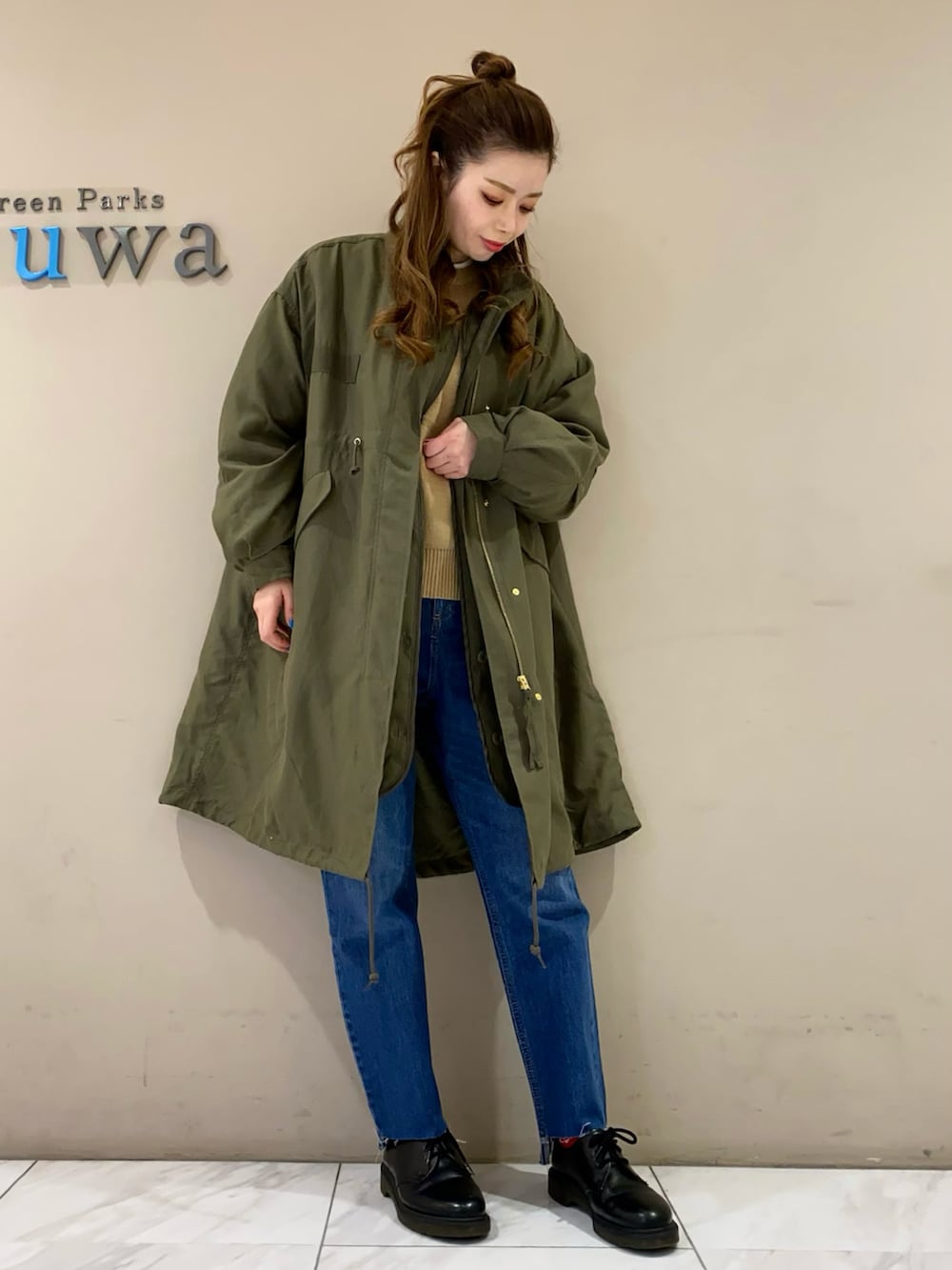 グリーン系のモッズコート、ブルー系のデニムパンツを着用したレディースの冬コーディネートの3枚目の写真