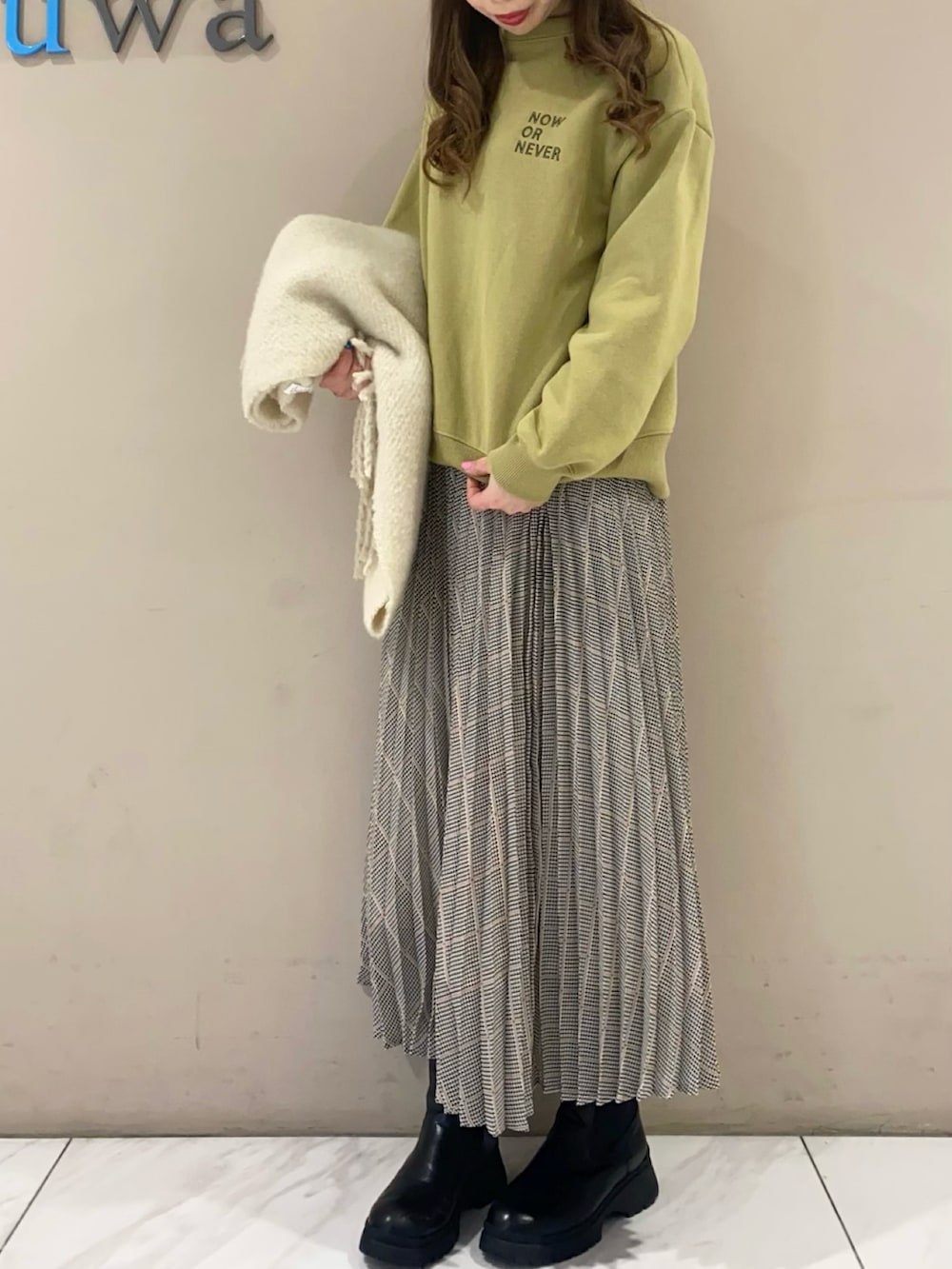 グリーン系のスウェット、ホワイト系のスカートを着用したレディースの冬コーディネートの3枚目の写真