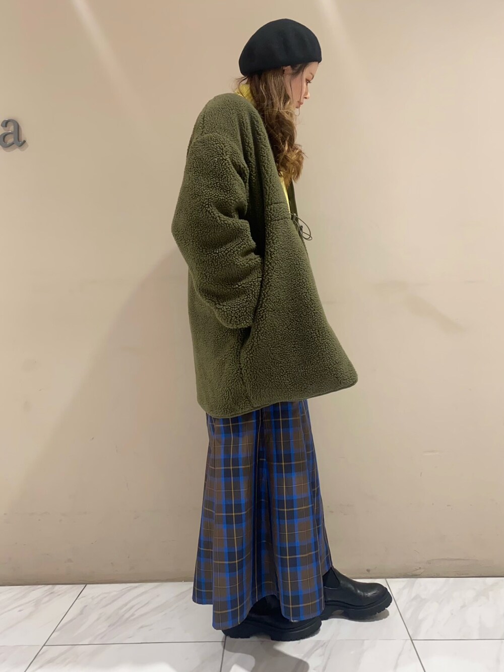 ブルー系のスカート、イエロー系のニット/セーター、グリーン系のその他アウターを着用したレディースの冬コーディネートの2枚目の写真