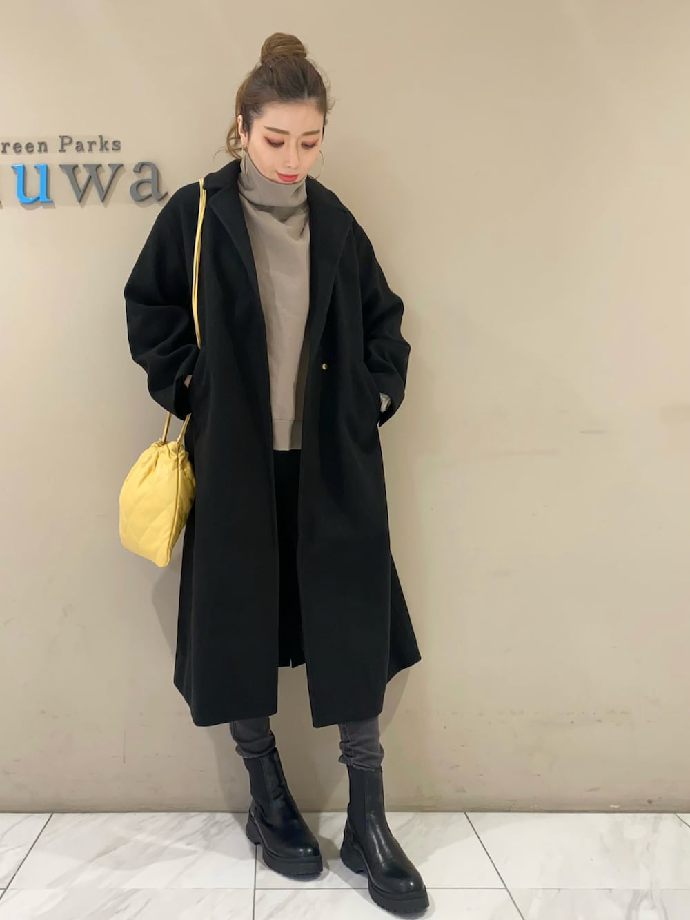 ベージュ系のスウェット、ブラック系のチェスターコート、ブラック系のデニムパンツを着用したレディースの冬コーディネートの2枚目の写真