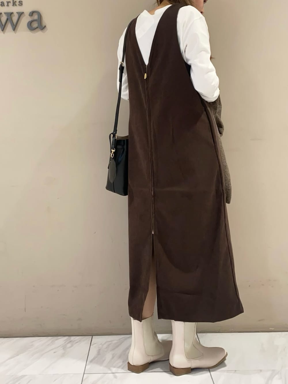 ブラウン系のジャンパースカート、ブラック系のブーツ、ブラック系のショルダーバッグを着用したレディースの冬コーディネートの4枚目の写真