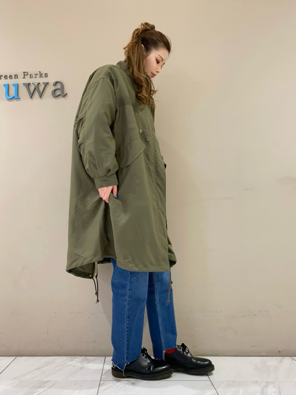 グリーン系のモッズコート、ブルー系のデニムパンツを着用したレディースの冬コーディネートの2枚目の写真