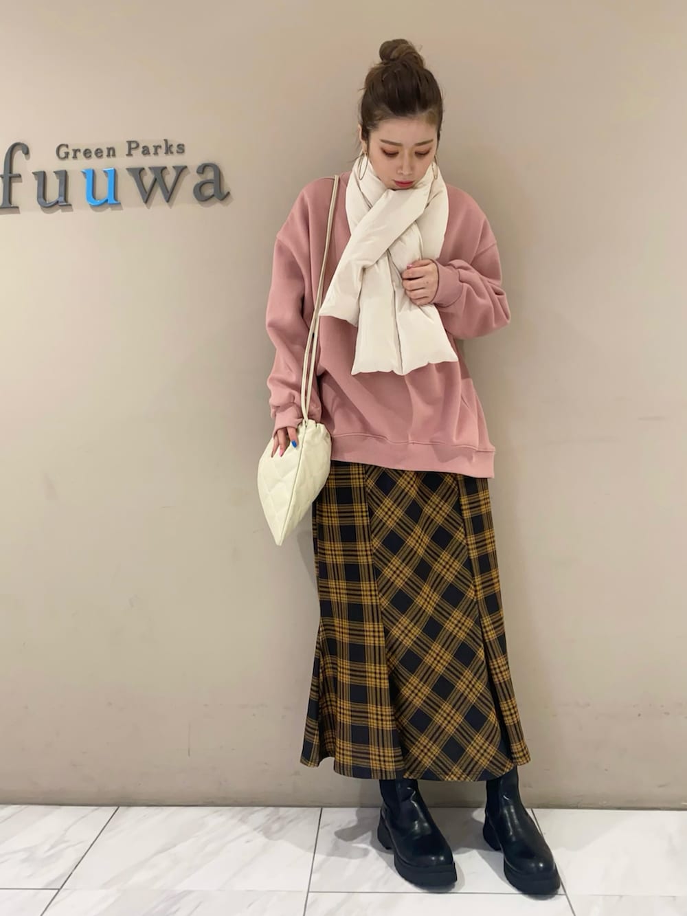 ピンク系のスウェット、イエロー系のスカート、ホワイト系のショルダーバッグを着用したレディースの冬コーディネートの2枚目の写真