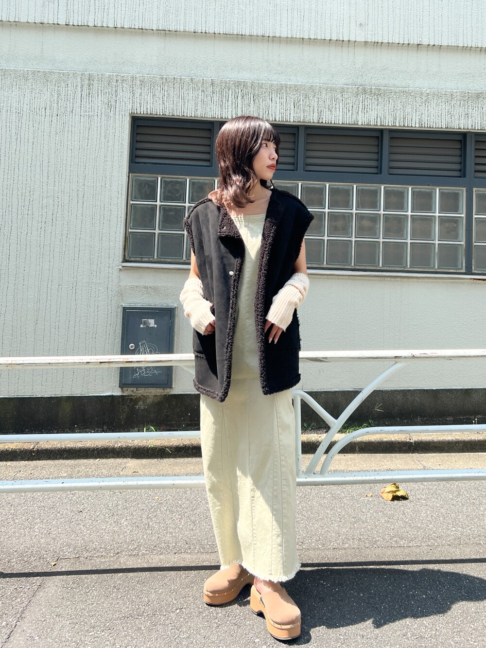 ベージュ系のジャンパースカート、ホワイト系のベスト、ホワイト系のアームカバーを着用したレディースの夏コーディネートの2枚目の写真