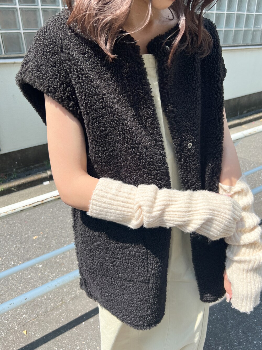 ベージュ系のジャンパースカート、ホワイト系のベスト、ホワイト系のアームカバーを着用したレディースの夏コーディネートの3枚目の写真