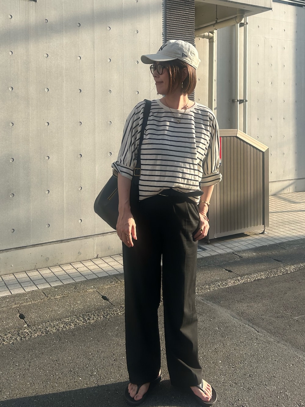 ブラック系のサンダル、その他のTシャツ/カットソー、ブラック系のショルダーバッグを着用したレディースの夏コーディネートの2枚目の写真