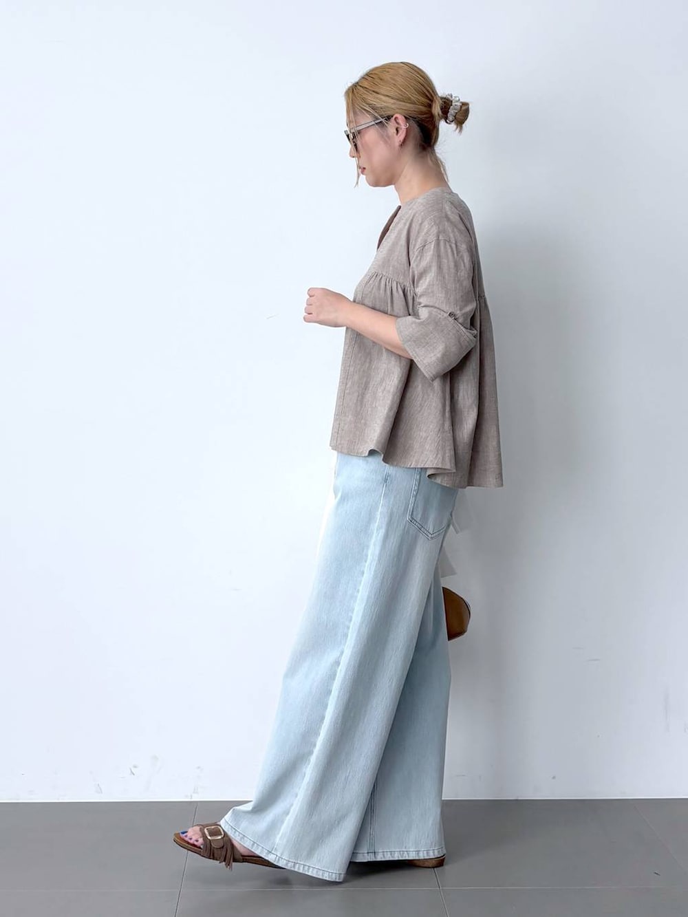ブルー系のデニムパンツ、ベージュ系のシャツ/ブラウス、ブラウン系のハンドバッグを着用したレディースの春コーディネートの4枚目の写真