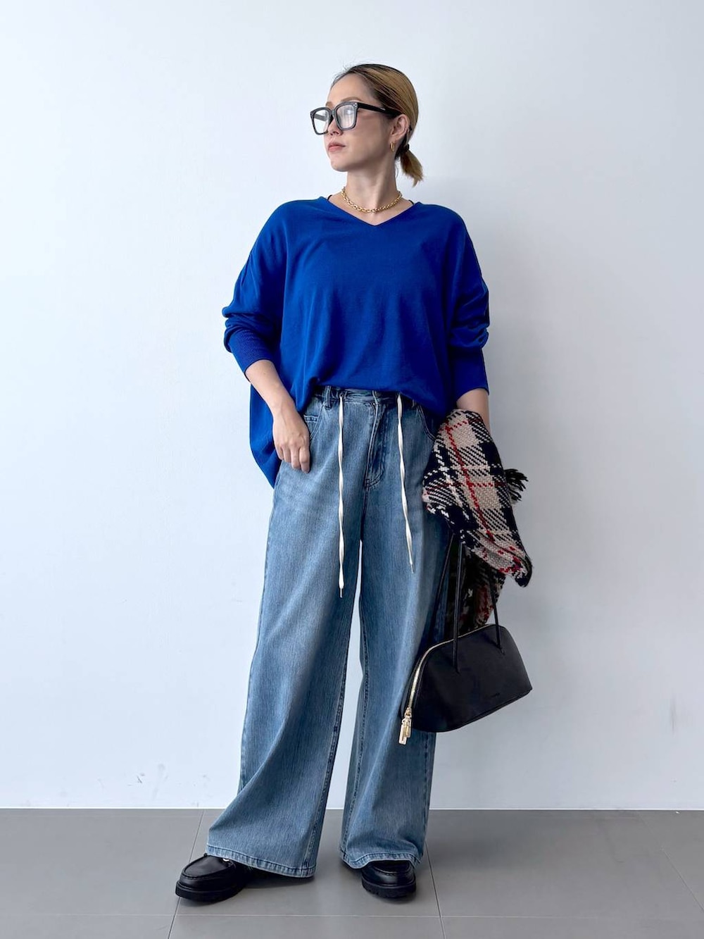 ブラック系のトートバッグ、ブルー系のデニムパンツ、ブラック系のローファーを着用したレディースの秋コーディネートの3枚目の写真
