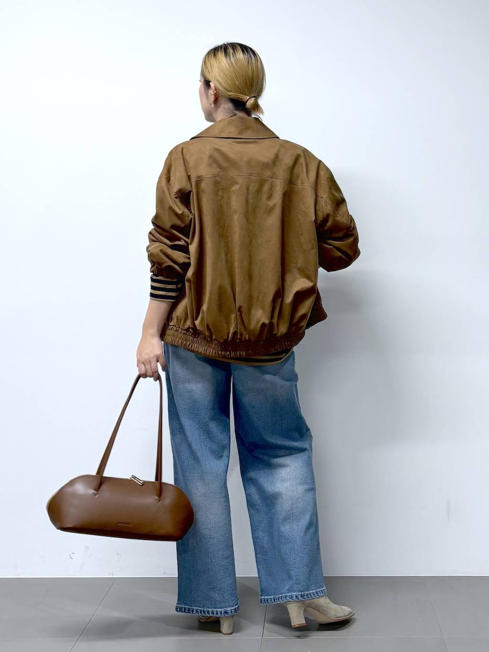 ブルー系のデニムパンツ、ブラウン系のトートバッグ、ベージュ系のTシャツ/カットソーを着用したレディースの秋コーディネートの6枚目の写真