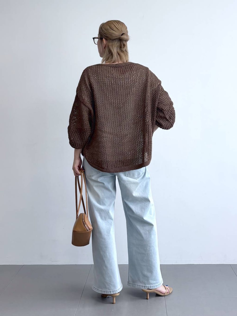 ブラウン系のニット/セーター、ブルー系のデニムパンツ、ブラウン系のハンドバッグを着用したレディースの冬コーディネートの4枚目の写真