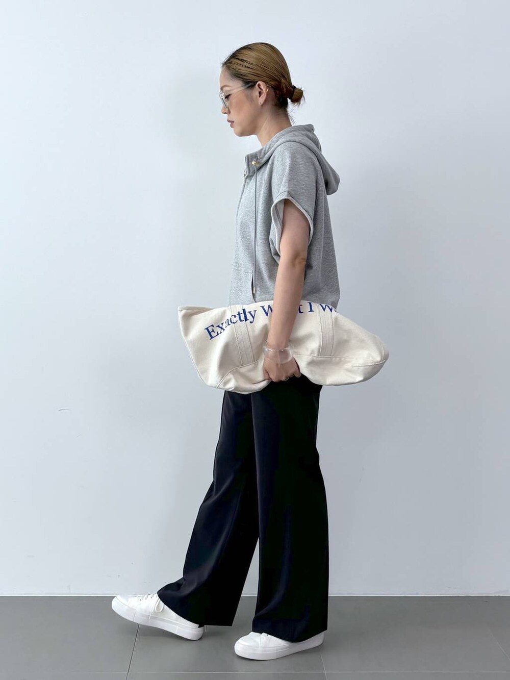 ホワイト系のトートバッグ、ホワイト系のスニーカー、ブラック系のスラックスを着用したレディースの夏コーディネートの3枚目の写真