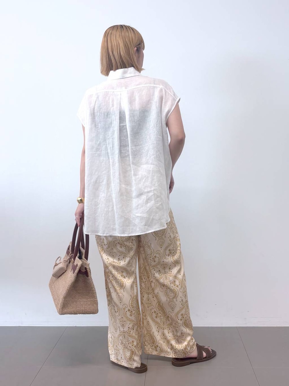 ベージュ系のその他パンツ、ベージュ系のかごバッグ、ホワイト系のシャツ/ブラウスを着用したレディースの春コーディネートの4枚目の写真