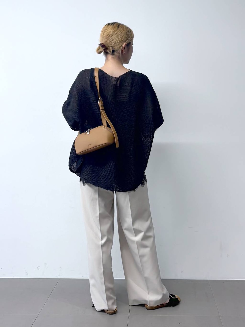 ブラック系のニット/セーター、ブラウン系のショルダーバッグ、グレー系のその他パンツを着用したレディースの春コーディネートの4枚目の写真