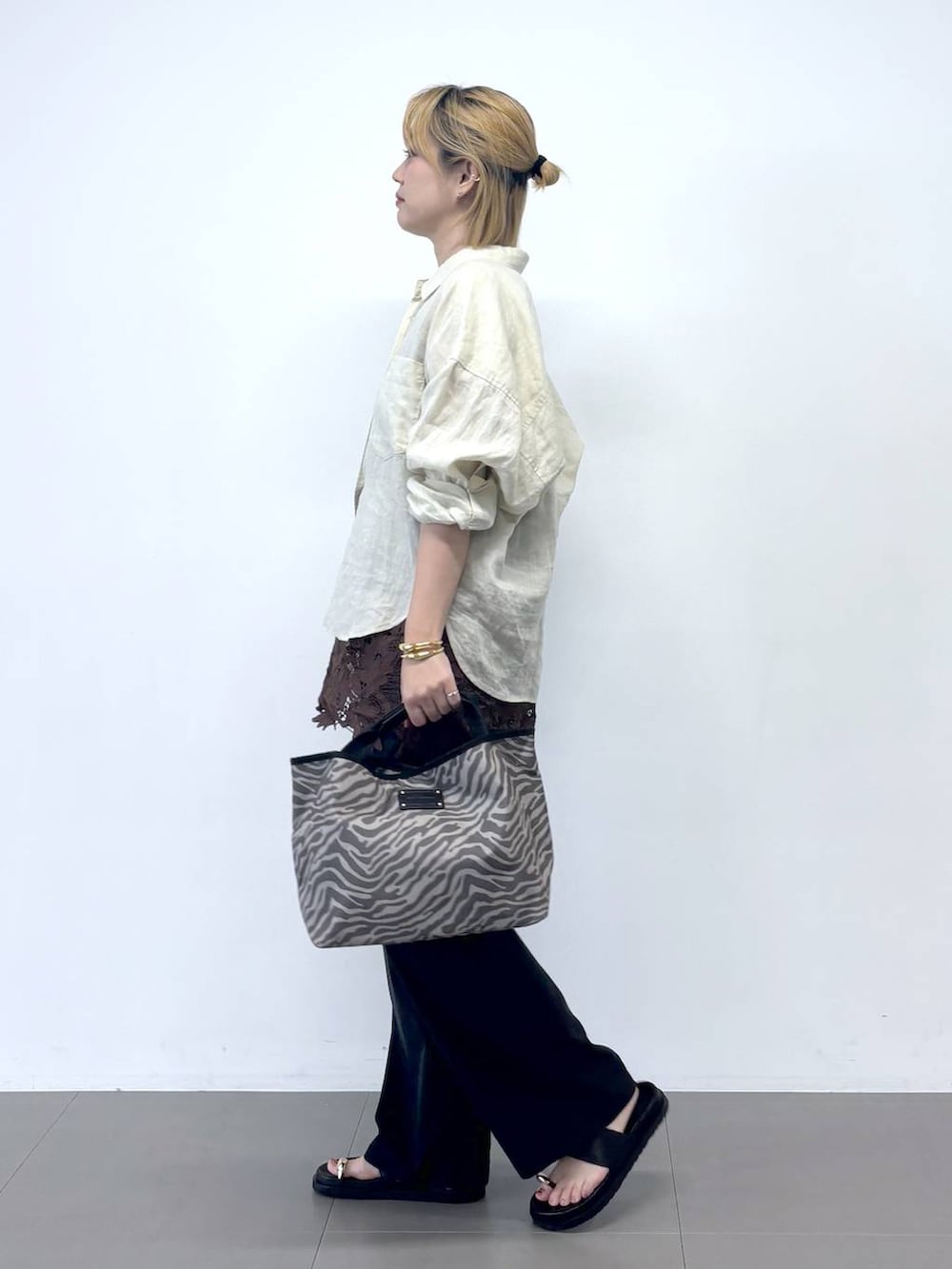 グレー系のトートバッグ、ブラック系のチノパンツ、ブラウン系のシャツ/ブラウスを着用したレディースの夏コーディネートの3枚目の写真
