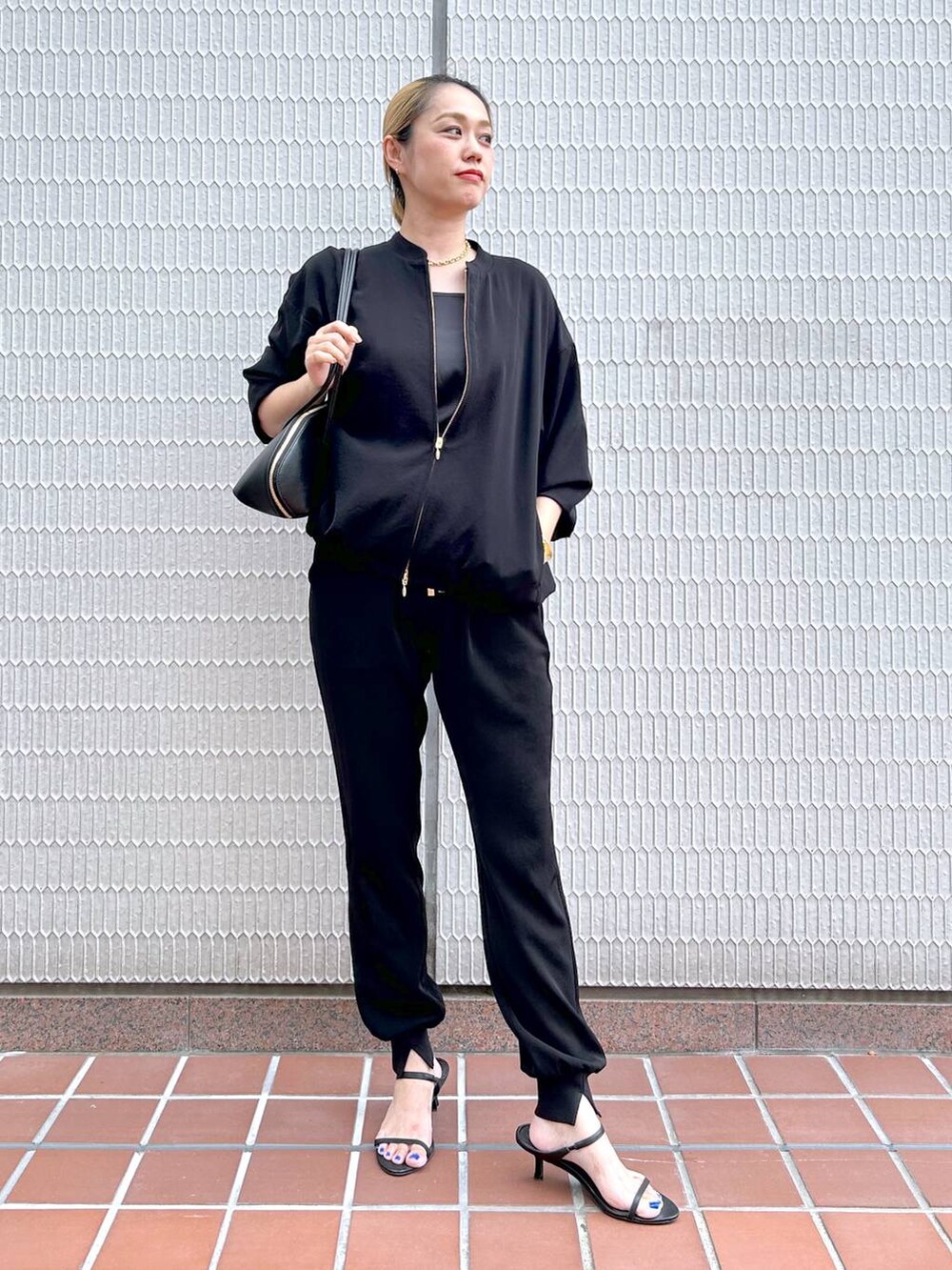 ブラック系のトートバッグ、ブラック系のブルゾン、ブラック系のサンダルを着用したレディースの秋コーディネートの2枚目の写真