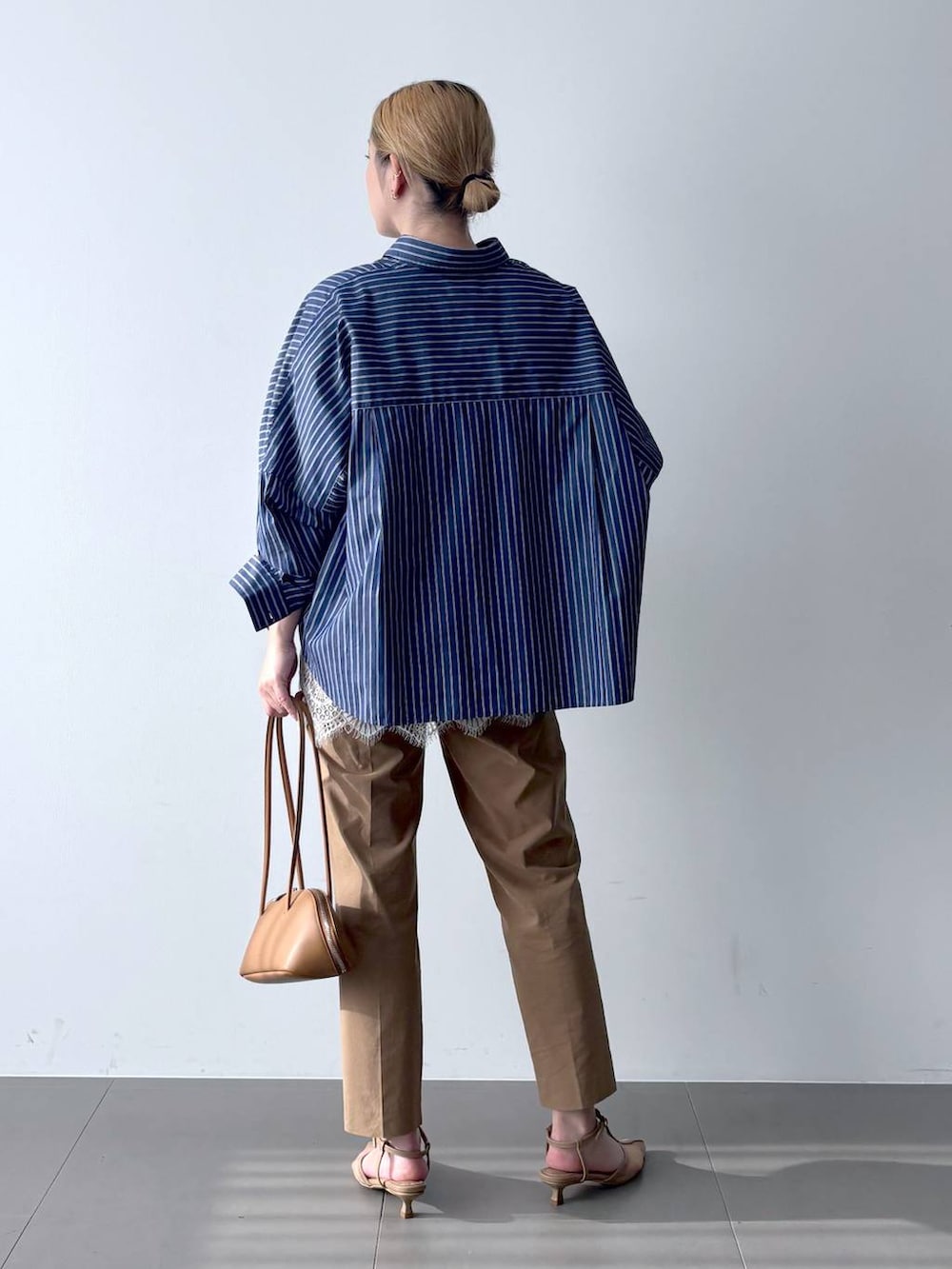 ブルー系のシャツ/ブラウス、ブラウン系のハンドバッグ、ベージュ系のその他パンツを着用したレディースの春コーディネートの5枚目の写真