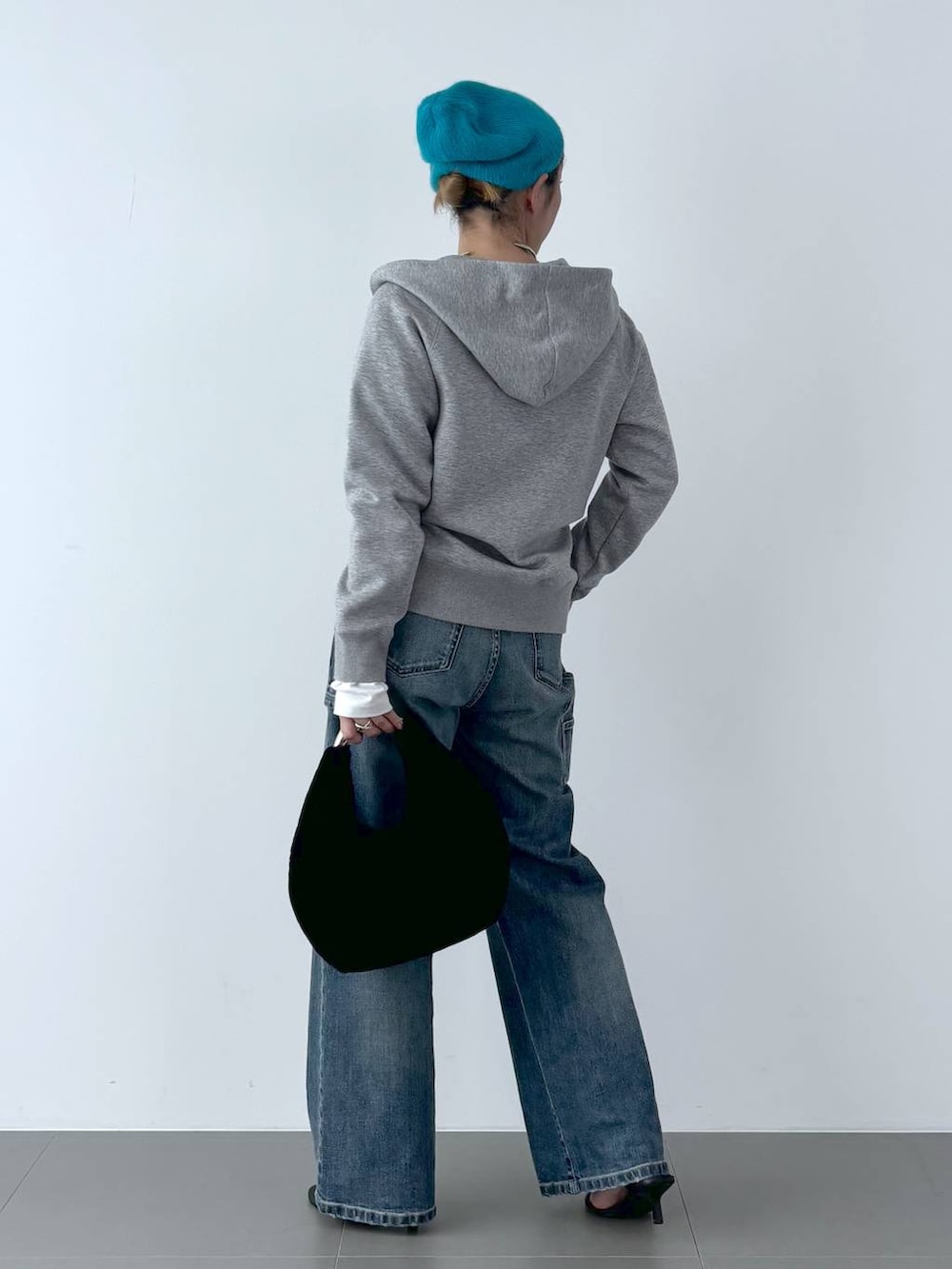 ブラック系のスリッポン、ブラック系のトートバッグ、ブルー系のデニムパンツを着用したレディースの秋コーディネートの5枚目の写真