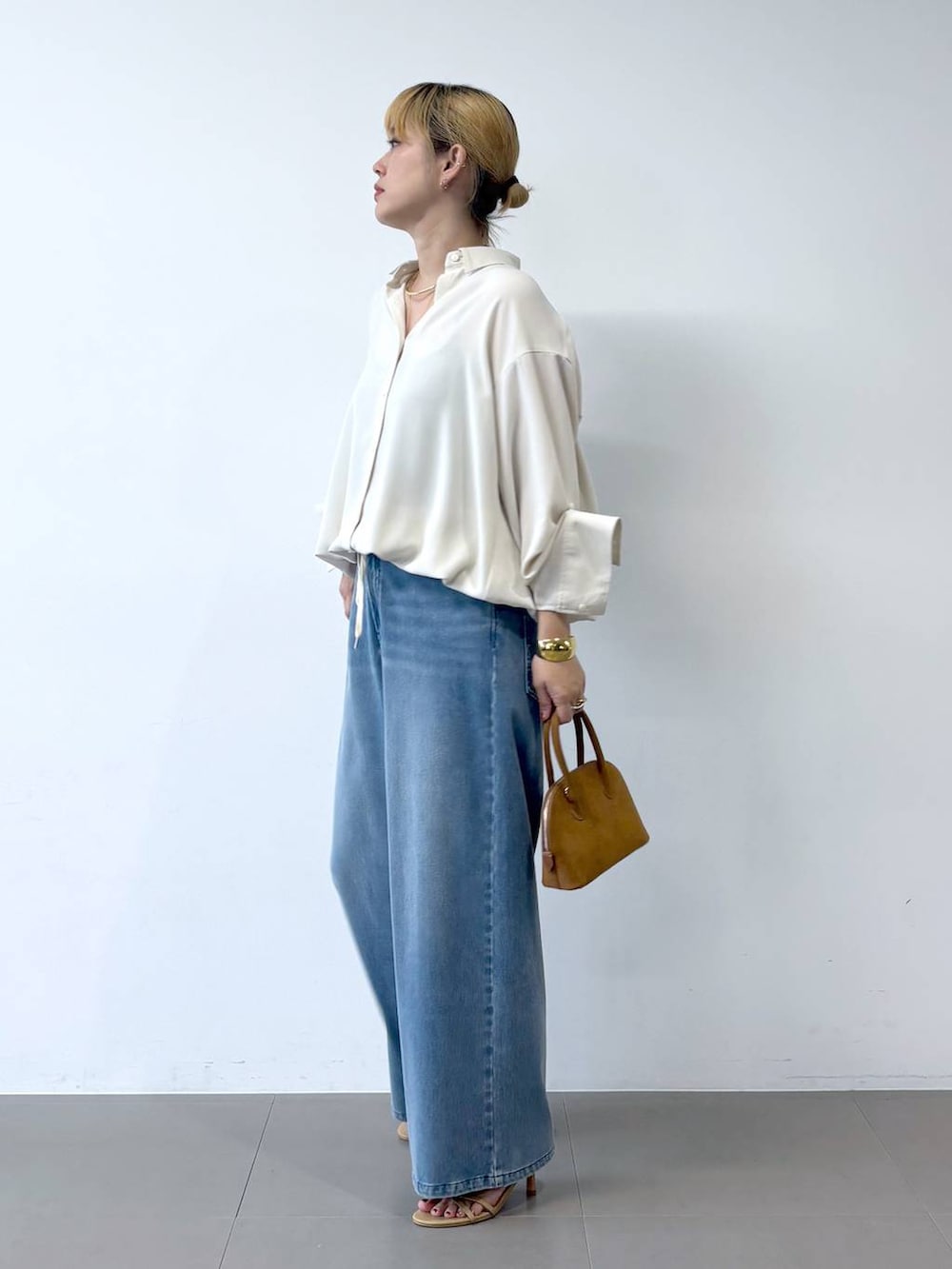 ブルー系のデニムパンツ、ベージュ系のサンダル、ホワイト系のシャツ/ブラウスを着用したレディースの夏コーディネートの3枚目の写真